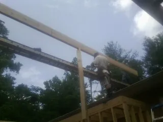 Carpenter setting a ridge beam over a new addition frame — Ice Dam Removal by Roofing Brothers in Anthon