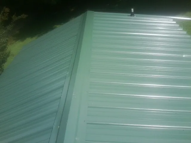 New green metal panels meeting at the ridge of a roof — Flat Roof Repair work by our crew in Anthon