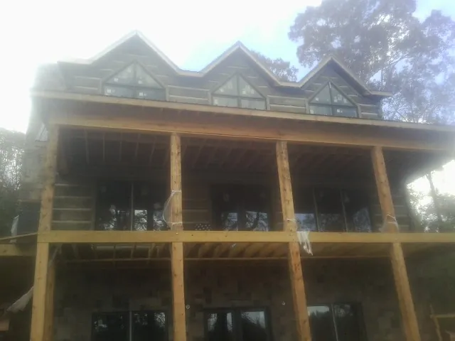 Dormers and porch framing on a large log home under construction — Roof Coating work by our crew in Anthon