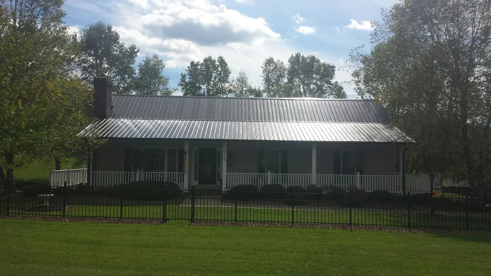 Gray metal roof on a brick ranch with a full width front porch — Gutter Guard Installation work by our crew in Anthon