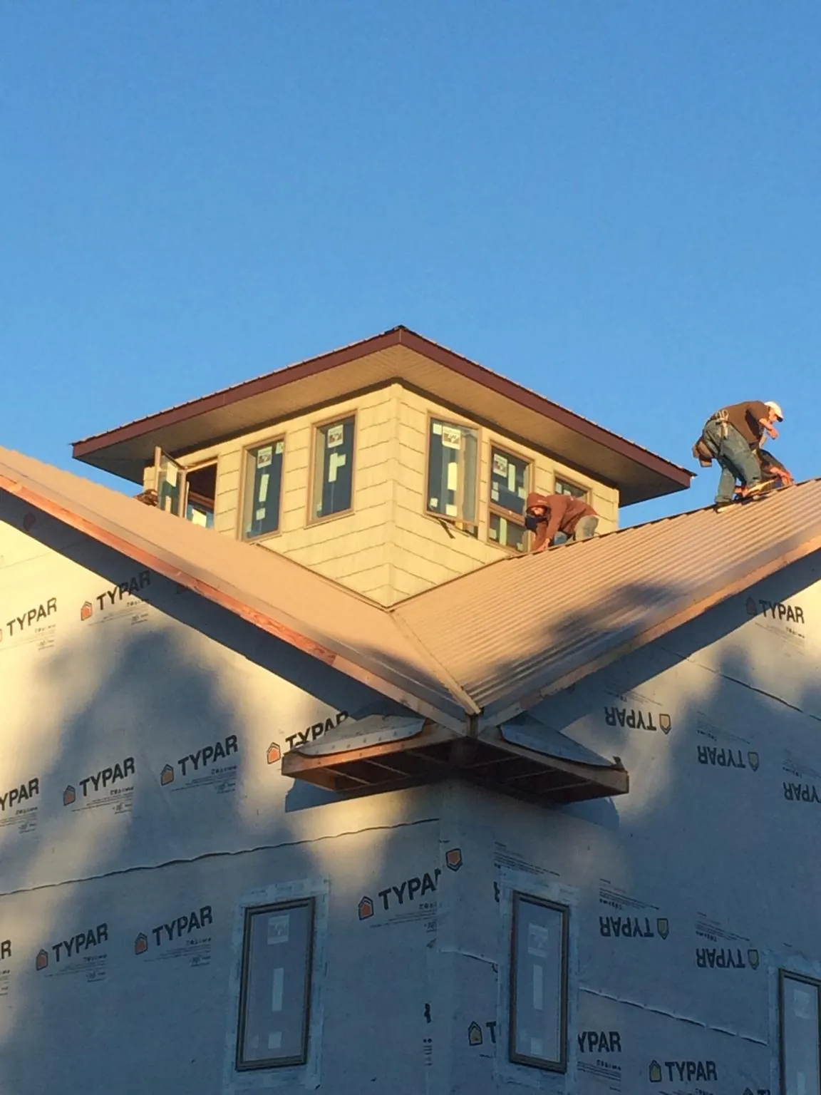 Roofers working around a rooftop cupola on a new metal roof at sunset — Roof Waterproofing in Anthon by Roofing Brothers